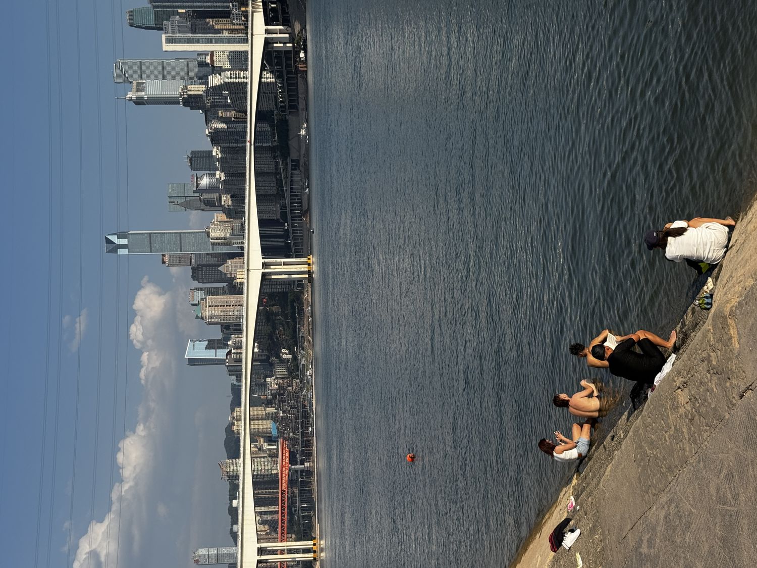 People relaxing beside the river with Chongqing’s skyline beyond